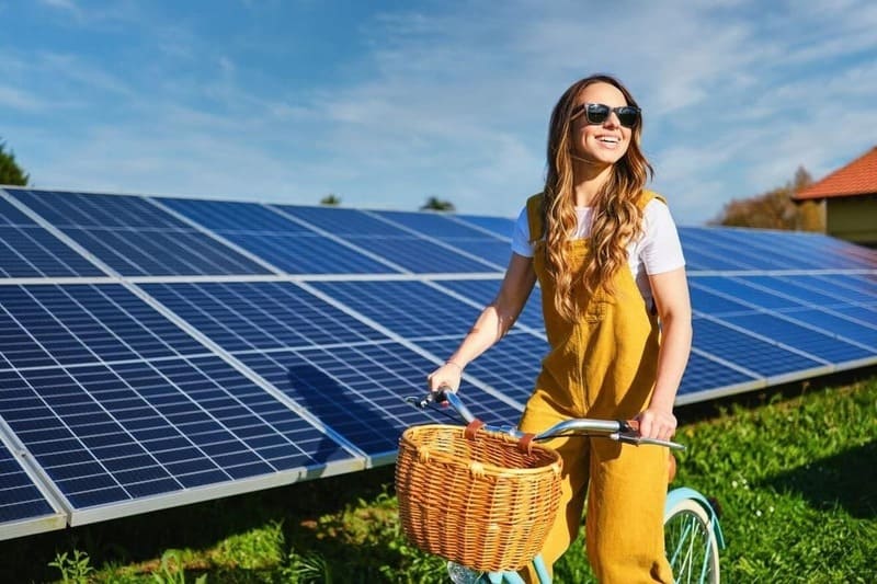 chica en bici pasea junto a paneles solares