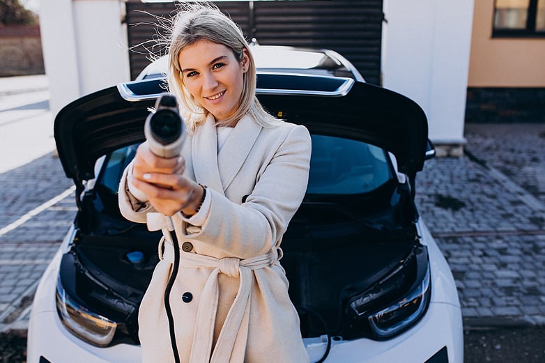 mujer con cable del cargador de coche eléctrico