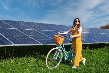 Chica paseando en bicicleta por placas solares