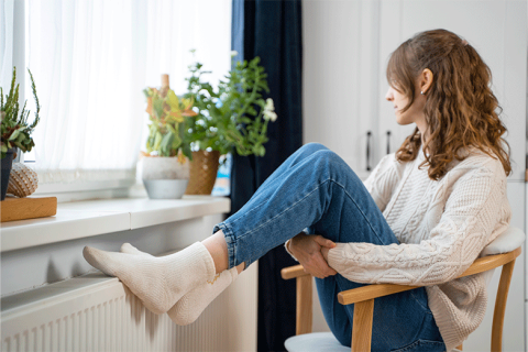 Mujer reposando los pies en el radiador