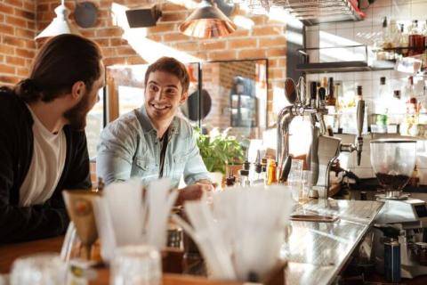 Clientes sentados en la barra de un bar con mucha luz natural