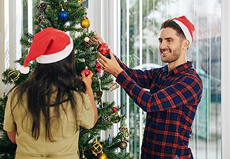 Empleados con gorros navideños decoran el árbol de navidad en oficina