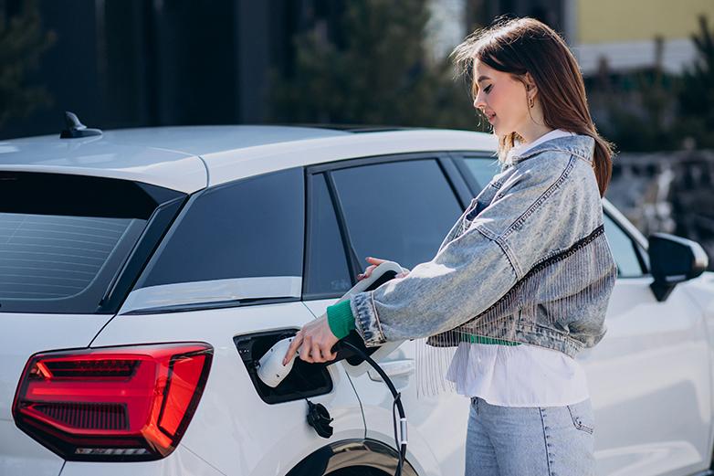 Mujer enchufando el cargador al coche eléctrico