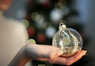 Mano sosteniendo bola de Navidad