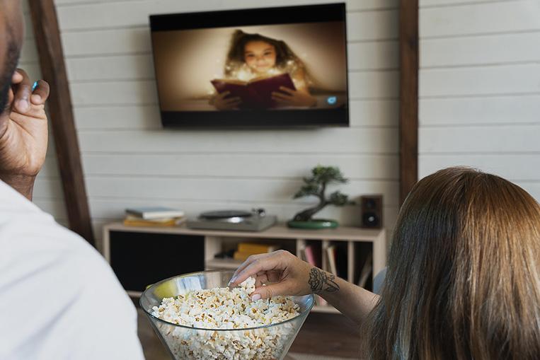 Pareja viendo la televisión comiendo palomitas