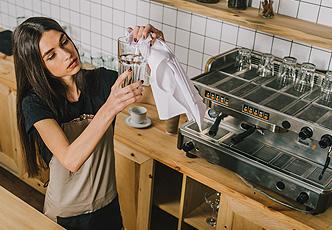 mujer en el restaurante secando vaso con un trapo